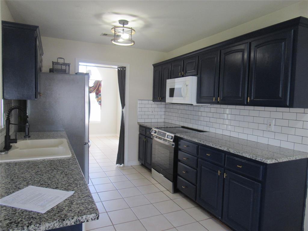 4019 East Fm 120 Denison, TX 75021 - Photo 12 of 39 a kitchen with stainless steel appliances granite countertop a stove a sink and a microwave