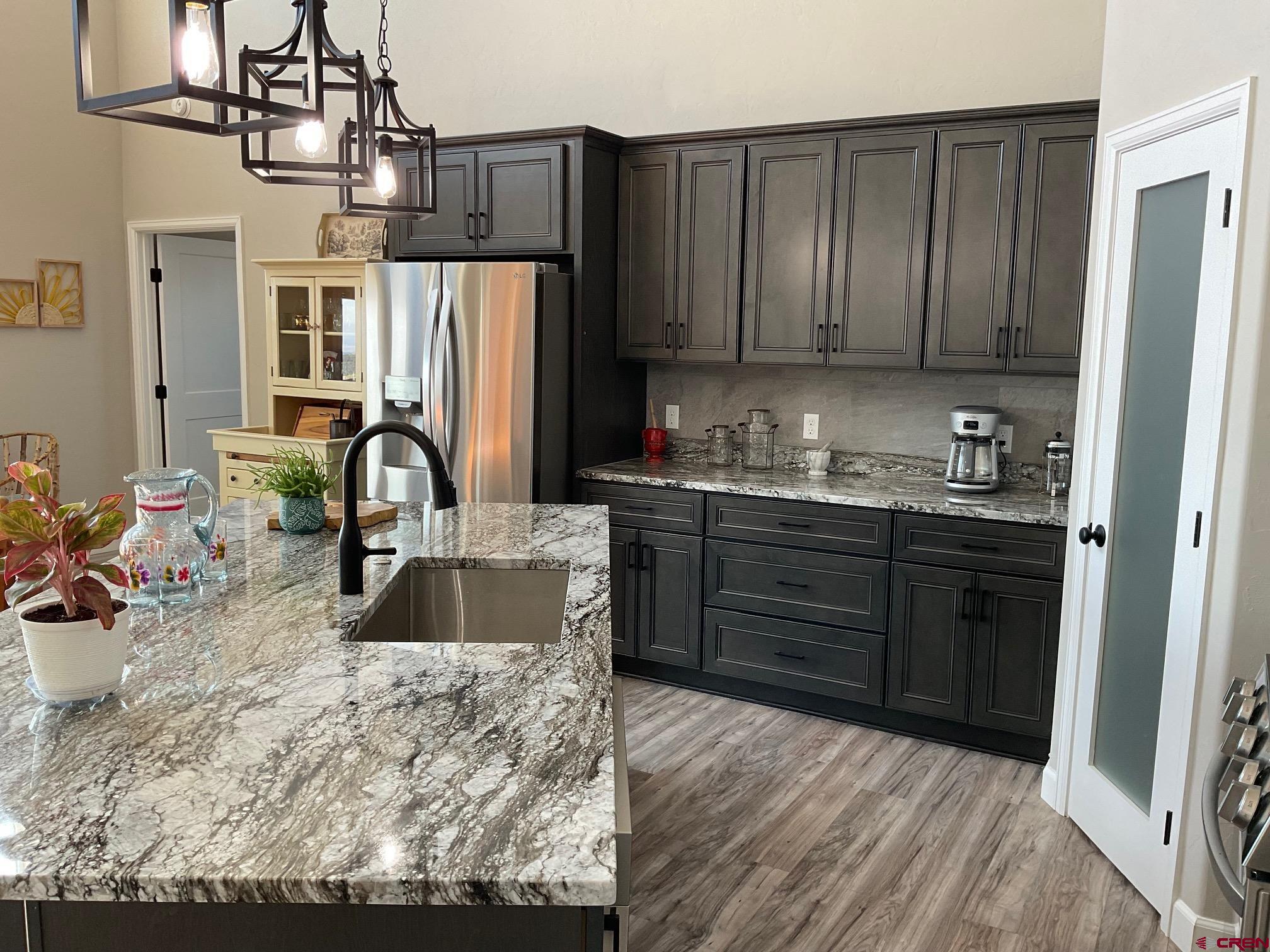 24203 Valley View Circle Cedaredge, CO 81413 - Photo 14 of 41 a kitchen with stainless steel appliances granite countertop a refrigerator a sink dishwasher and wooden cabinets with wooden floor