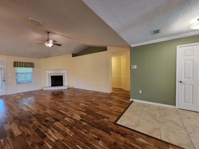 a view of empty room with kitchen and fireplace