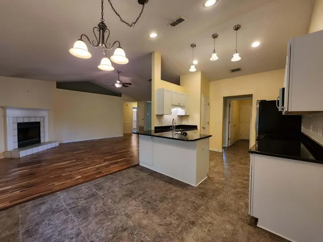 a view of a kitchen with kitchen island a sink stainless steel appliances and a chandelier