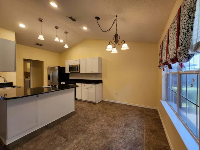 a large kitchen with stainless steel appliances a large counter top a stove and a chandelier