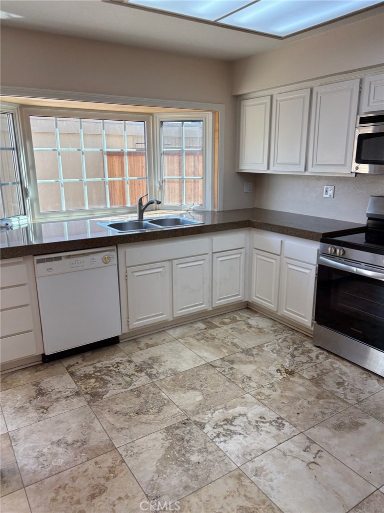 18243 Crater Lake Court Fountain Valley, CA 92708 - Photo 7 of 13 a kitchen with stainless steel appliances granite countertop a stove a sink and white cabinets