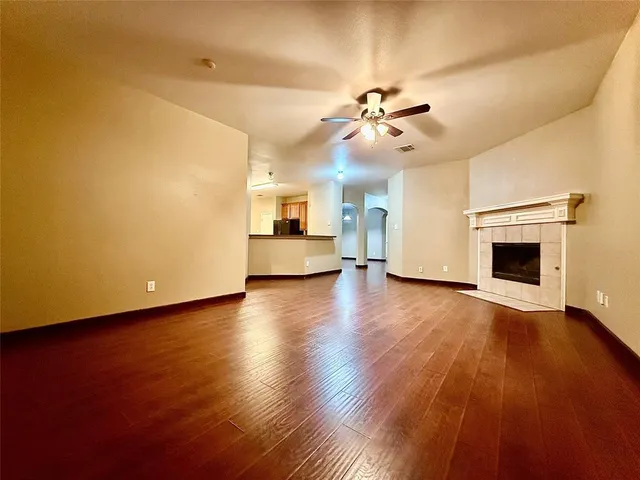 a view of a livingroom with a fireplace a ceiling fan and wooden floor