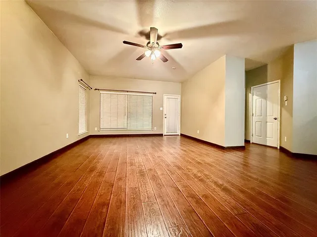 a view of empty room with wooden floor and ceiling fan