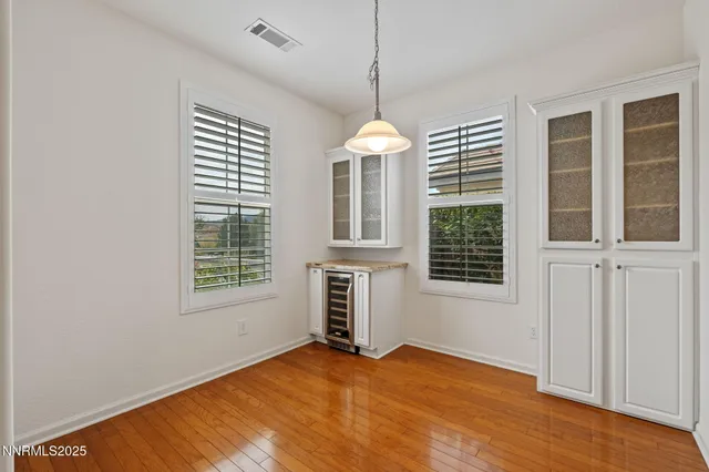 an empty room with chandelier fan and windows