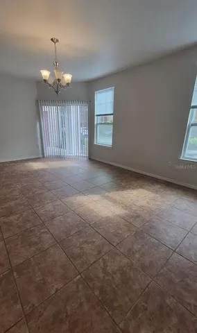 an empty room with chandelier fan and windows