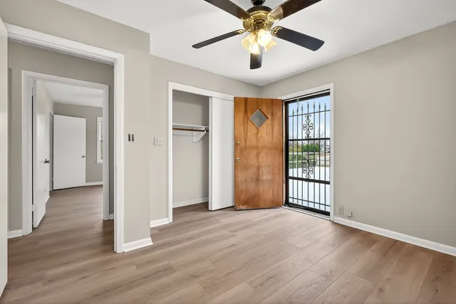 an empty room with wooden floor chandelier and windows