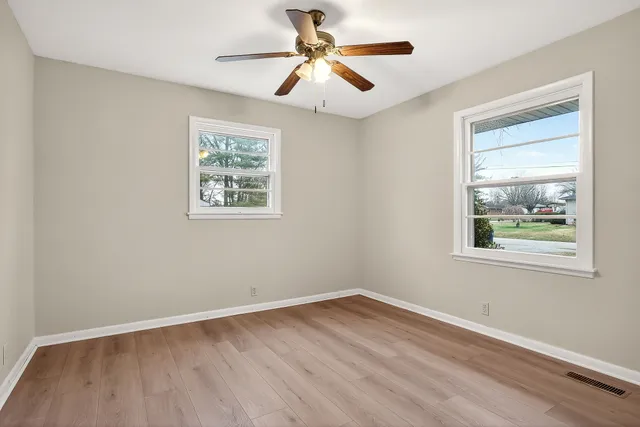 a view of an empty room with window and wooden floor