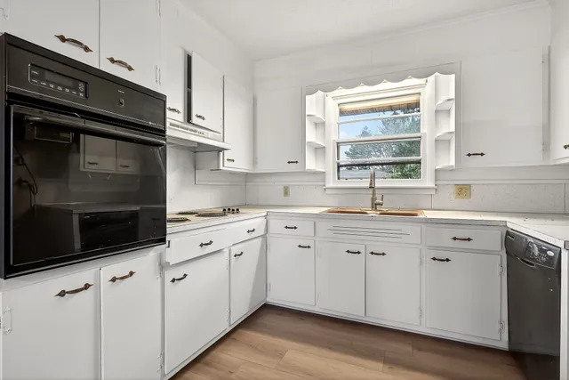 a kitchen with granite countertop white cabinets appliances a sink and a window