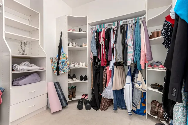 a view of walk in closet with clothes and shoes