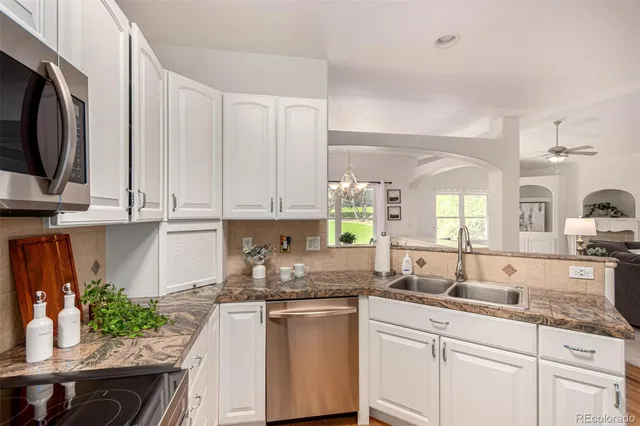 a kitchen with granite countertop white cabinets and white appliances
