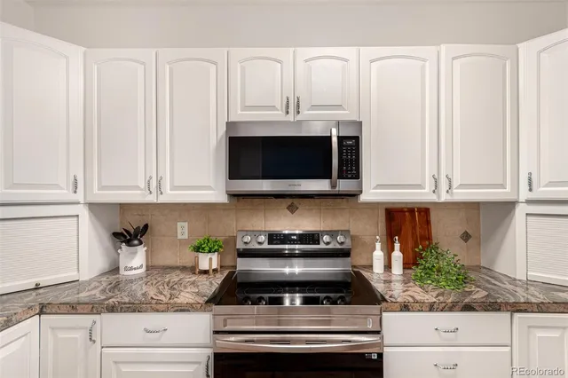 a kitchen with granite countertop white cabinets and stainless steel appliances