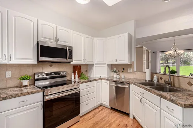 a white kitchen with granite countertop white cabinets and white stainless steel appliances