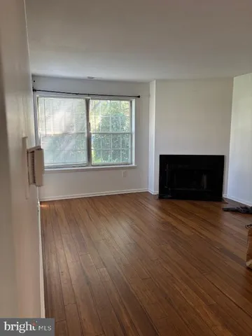 an empty room with wooden floor fireplace and windows