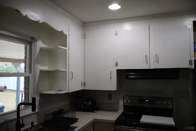 a kitchen with a sink a stove a refrigerator and white cabinets