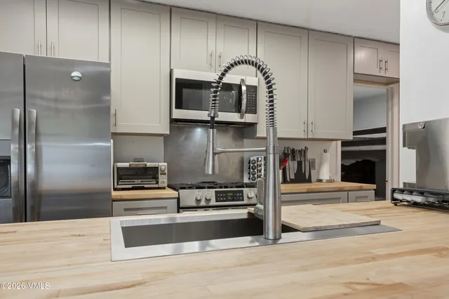 a kitchen with stainless steel appliances kitchen island granite countertop a refrigerator a stove and a sink with wooden floor