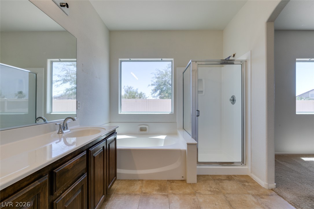 5150 Riverside Run Court North Las Vegas, NV 89081 - Photo 43 of 50 A bright bathroom with a vanity, bathtub, and glass-enclosed shower, offering a refreshing start to your day.