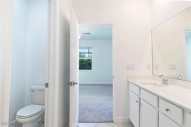 a bathroom with a granite countertop sink a toilet and a mirror