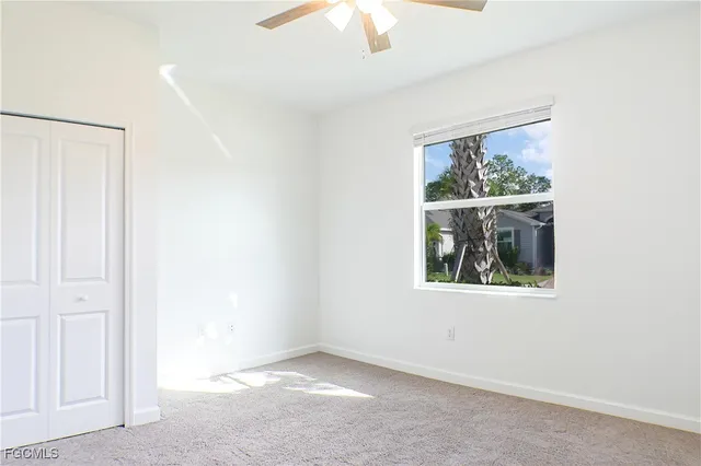 an empty room with a window and a ceiling fan