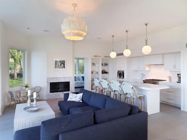 a living room with stainless steel appliances a fireplace and a chandelier