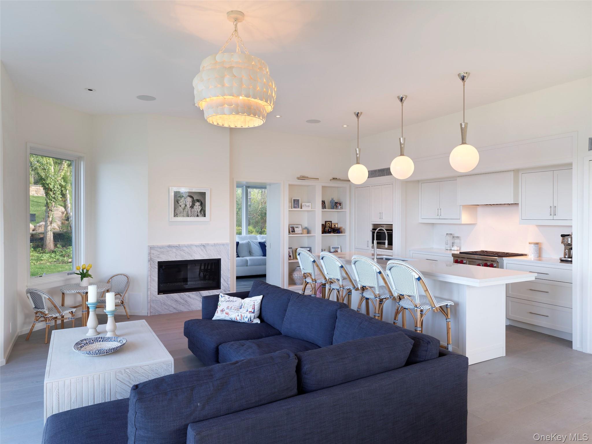 2 Sun Court Hampton Bays, NY 11946 - Photo 6 of 35 a living room with stainless steel appliances a fireplace and a chandelier