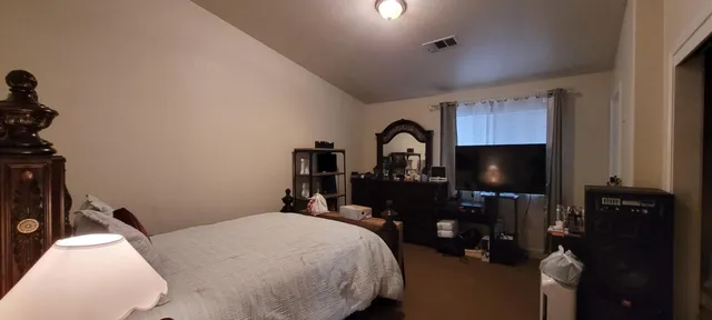 a bedroom with a bed and a flat tv screen on the dresser