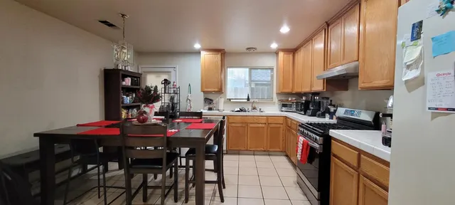 a kitchen with stainless steel appliances kitchen island granite countertop a stove a sink a dining table and chairs
