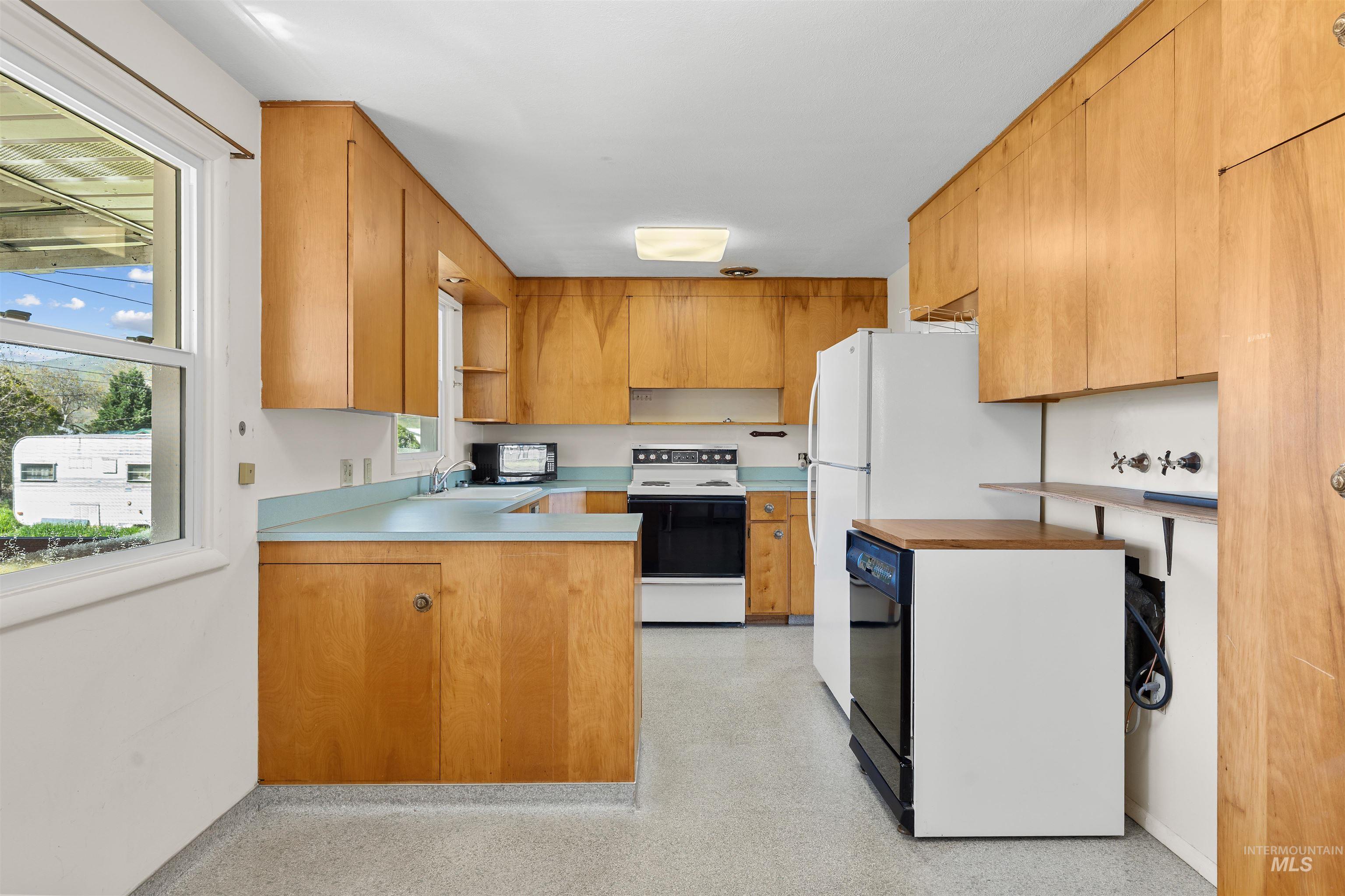 1148 Webster Street Clarkston, WA 99403 - Photo 4 of 29 Kitchen featuring a peninsula, white appliances, open shelves, light countertops, and light floors