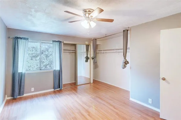 an empty room with wooden floor chandelier fan and windows