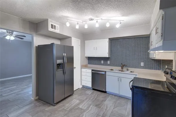 a kitchen with stainless steel appliances a stove a sink and white cabinets