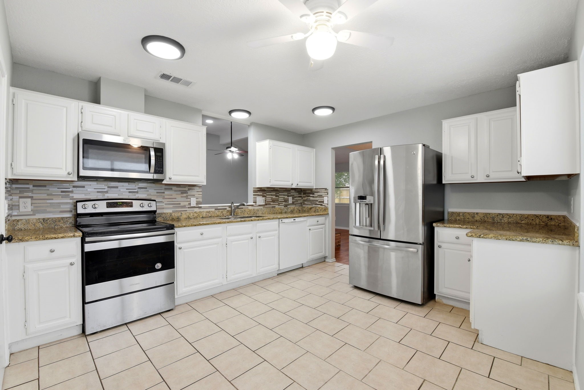 21330 Golden Dove Drive Spring, TX 77388 - Photo 10 of 29 The chef’s kitchen is highly functional, featuring crisp white cabinetry, durable tile floors, and a modern suite of stainless steel appliances.