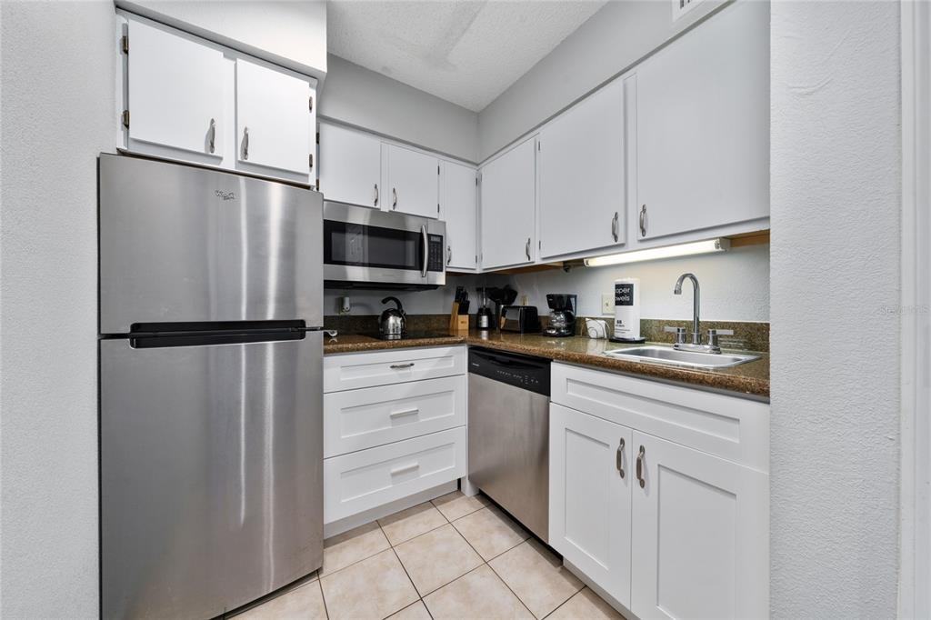 3100 Parkway Boulevard, Unit 511 Kissimmee, FL 34747 - Photo 9 of 40 a kitchen with stainless steel appliances granite countertop a refrigerator sink and cabinets