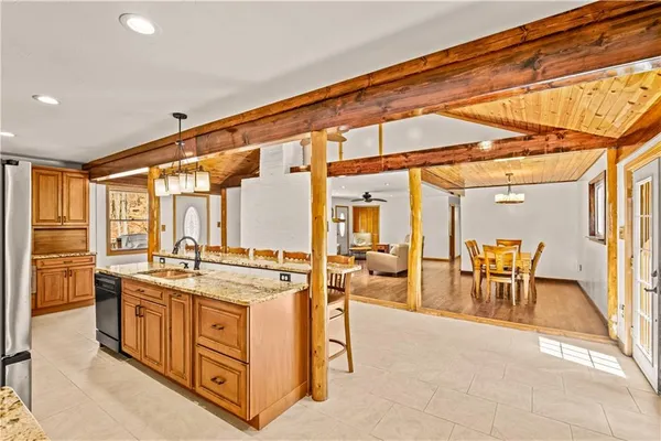 a open kitchen with stainless steel appliances granite countertop a stove top oven a sink and a dining table with the view of living room