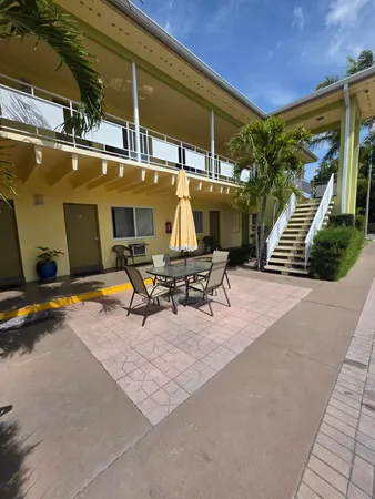 a view of a patio with a table and chairs under an umbrella with a small yard