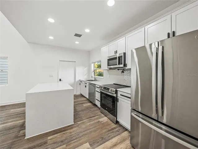 a kitchen with stainless steel appliances a refrigerator and a stove top oven