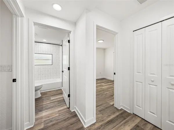 a view of a hallway with wooden floor and closet area