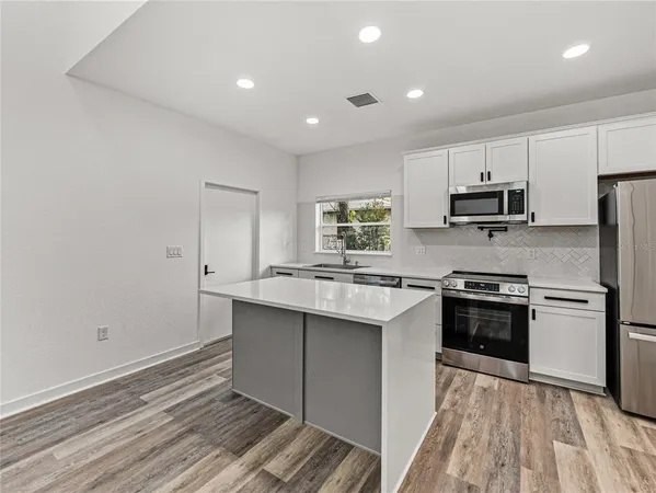 a kitchen with kitchen island granite countertop a sink cabinets and stainless steel appliances