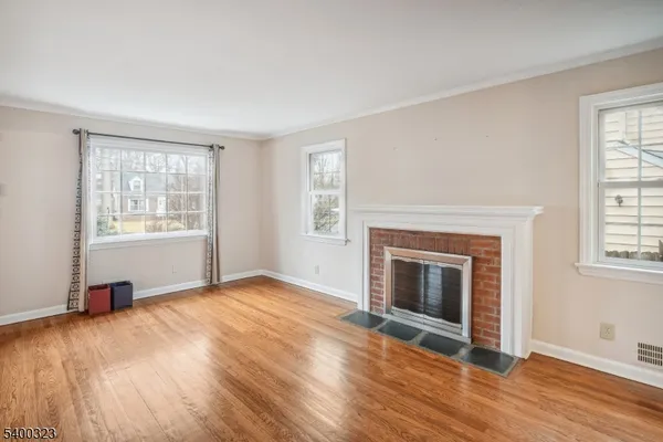 an empty room with windows fireplace and wooden floor