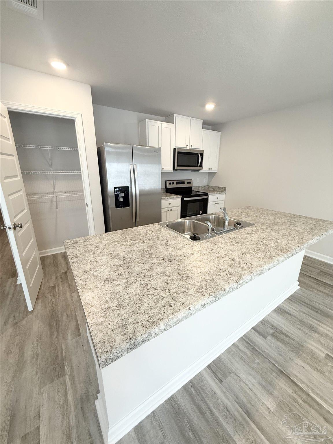 4335 Redbay Court Pace, FL 32571 - Photo 13 of 30 a view of a kitchen with kitchen island a sink wooden floor and counter top space