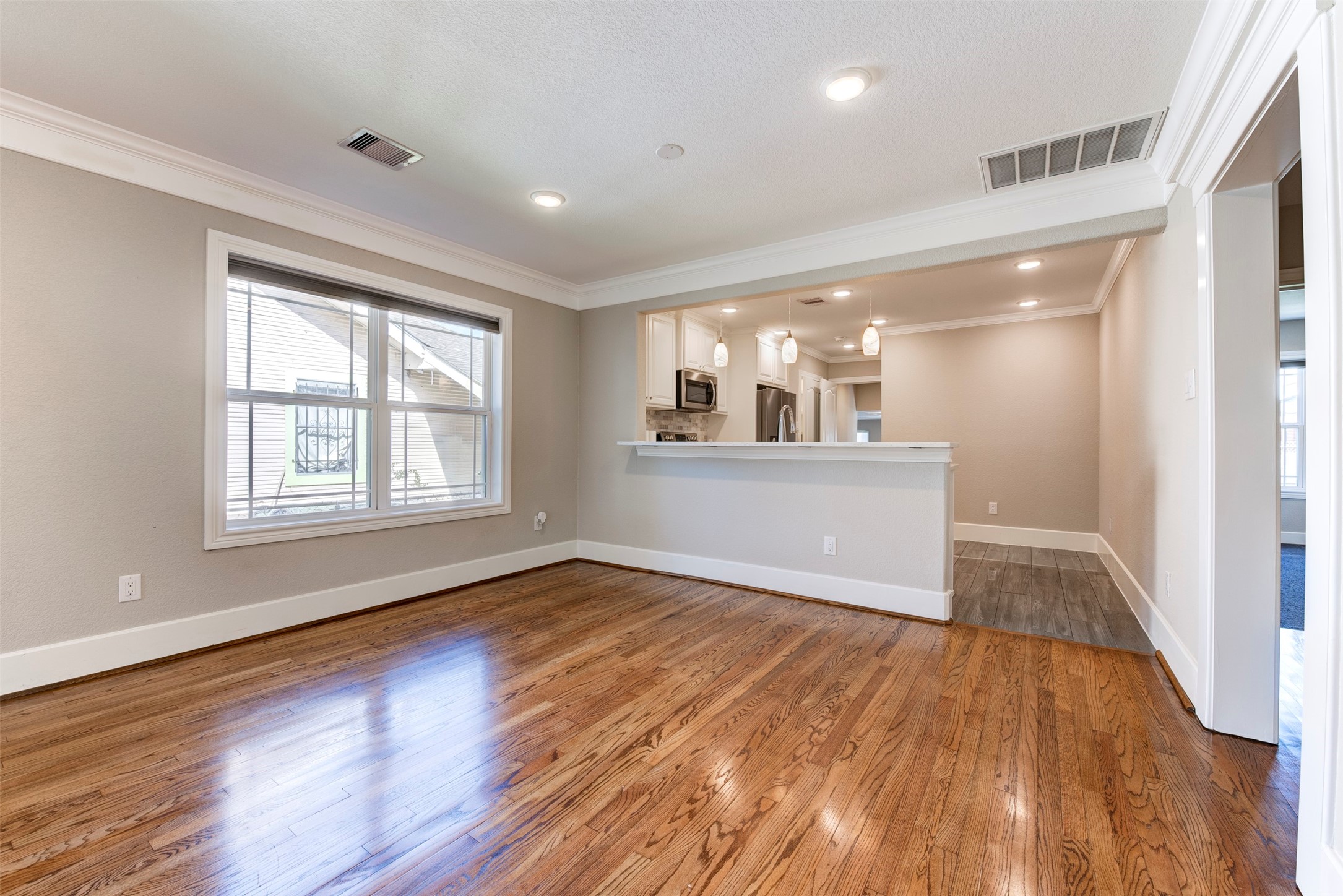 109 Dresden Street Houston, TX 77012 - Photo 12 of 43 Bright and spacious living area with hardwood floors, large window, and an open concept kitchen featuring a breakfast bar and modern appliances.