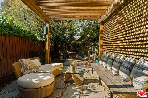 a view of backyard with table and chairs potted plants and large tree