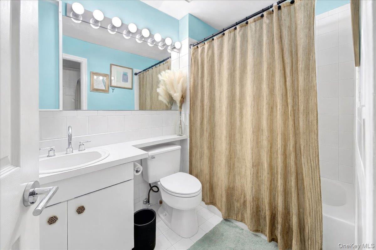37 Harbor Lane, Unit 2A New Rochelle, NY 10805 - Photo 15 of 22 a bathroom with a sink a toilet a mirror and shower curtain