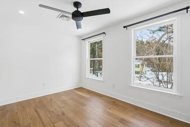 a view of an empty room with a window and wooden floor