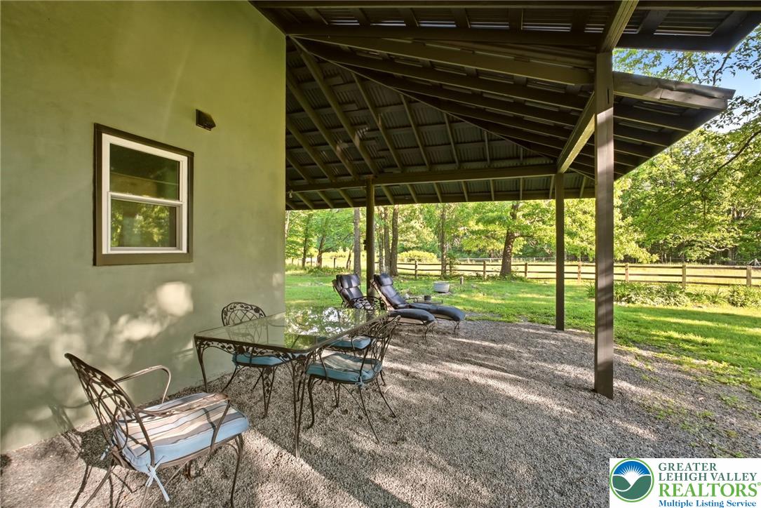 9033 Loop Road Slatington, PA 18080 - Photo 18 of 53 An inviting covered patio area offers a tranquil outdoor retreat overlooking lush greenery and a wooden fence.