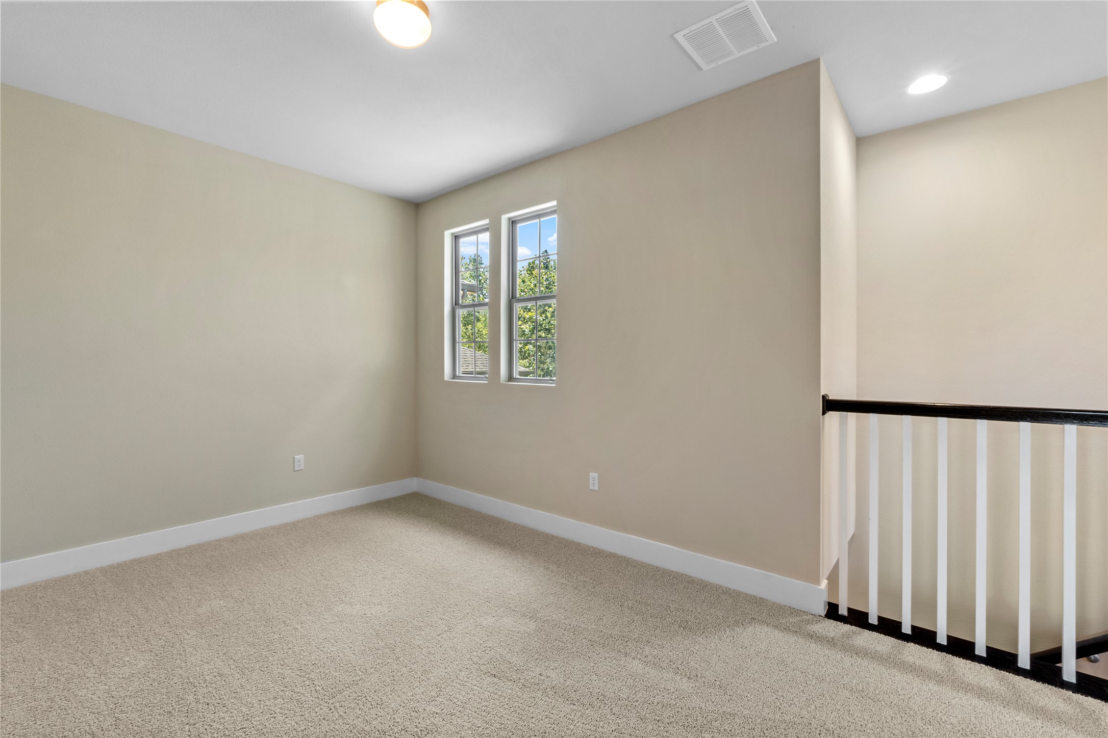 1709 Lawrence Street, Unit 5 Austin, TX 78741 - Photo 21 of 40 An open loft space features carpet flooring and views of surrounding greenery through paired windows.