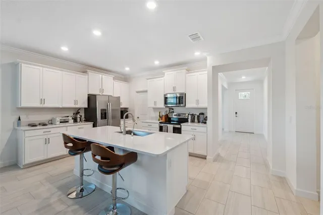 a kitchen with sink a refrigerator and chairs