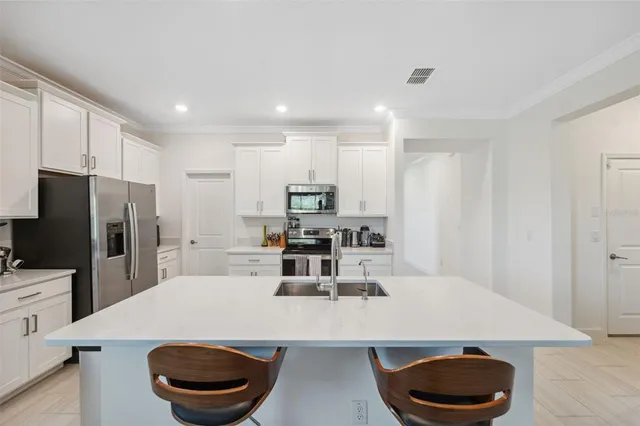 a kitchen with a sink a stove a refrigerator and white cabinets