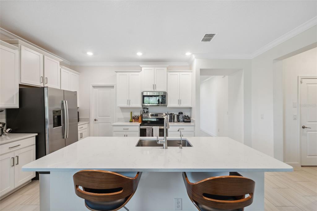 16787 Shell Bay Drive Land O Lakes, FL 34638 - Photo 9 of 54 a kitchen with sink a refrigerator and chairs