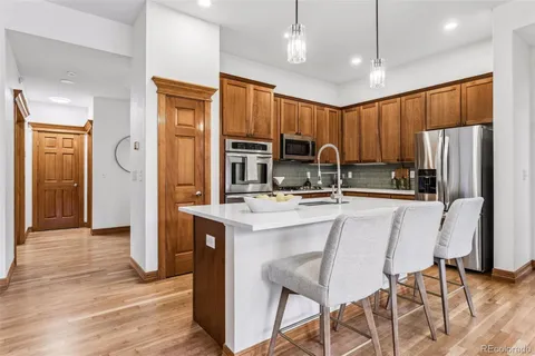 a kitchen with stainless steel appliances granite countertop a stove a sink dishwasher a dining table and chairs with wooden floor