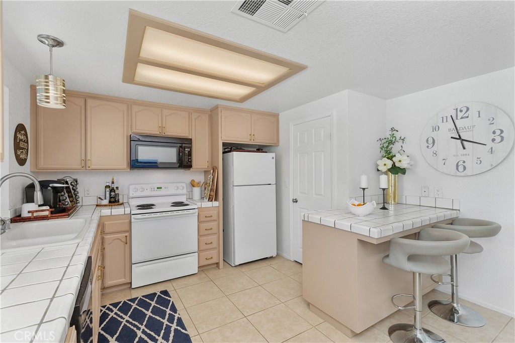 78680 Saguaro Road La Quinta, CA 92253 - Photo 11 of 30 a kitchen with stainless steel appliances granite countertop a sink a stove a refrigerator cabinets and chairs